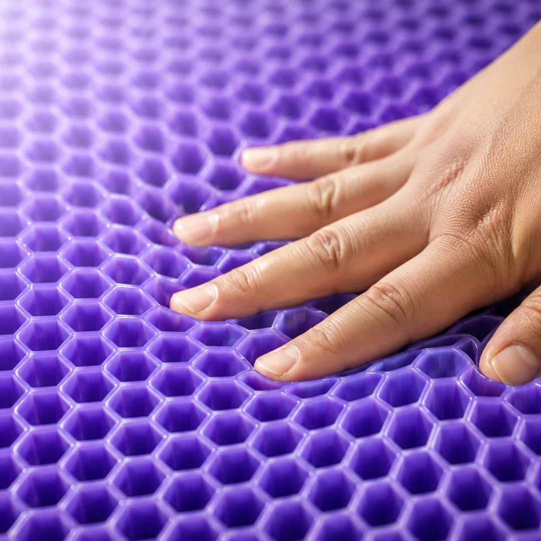 A hand pressing into the violet honeycomb gel cells of the Miravae cushion
